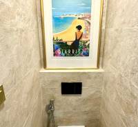 Háromszobás lakás WC-je, WC fölött egy képpel és csempével.