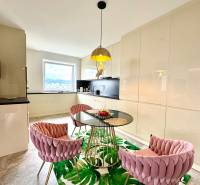 Étkező sarok üveg asztallal és rózsaszín székekkel egy háromszobás lakásban.