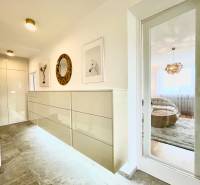 Folyosó egy 3 szobás lakásban csempézett padlóval, dekoratív képekkel és tükörrel.