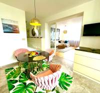 Étkező sarok kerek asztallal, székekkel és televízióval egy háromszobás lakásban.