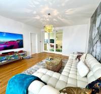 Nappali egy háromszobás lakásban, stílusos ülőgarnitúrával és falra szerelt televízióval.