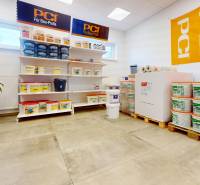 Építőanyagokkal ellátott üzlethelyiség, polcok vödrökkel, fa dekorú padló.