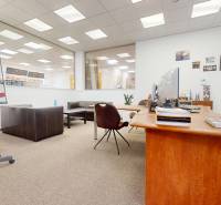 Kereskedelmi helyiség faasztallal, bőrfotelekkel és konferenciákhoz használt táblával.