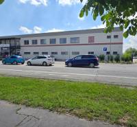 Kereskedelmi helyiségek a Trnava-i Strojárenská utcában, parkolóval és kerékpárosokkal.