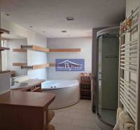 Fürdőszoba egy kétszobás lakásban, káddal, zuhanyzóval és polcokkal.