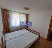 Hálószoba egy kétszobás lakásban ággyal, függönyökkel és fa dekorációjú padlóval.