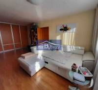 Világos nappali egy kétszobás lakásban, fa dekor padlóval és fehér kanapéval.