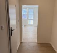 Garzonlakás fa hatású padlóval és nagy ablakokkal világos belső teret biztosít.