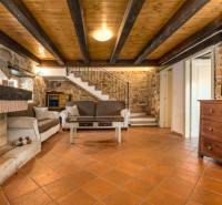 Kandallós szoba egy villában, fa mintázatú padlóval és kőfalakkal.