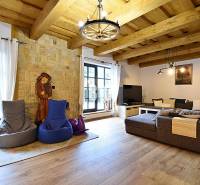 Hegyi ház belső tere kőfallal, nagy kanapéval és fa dekorációjú padlóval.