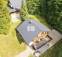 Házikó Terchován, erdővel körülvéve, fa terasszal és szomszédos kerttel.