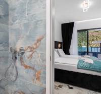 Fürdőszoba márványburkolattal és hálószoba egy villában tengerre néző kilátással.