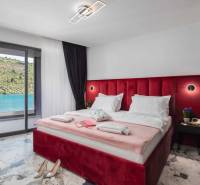 Hálószoba egy villában nagy ággyal és kilátással a tóra, márványmintás padlóval.