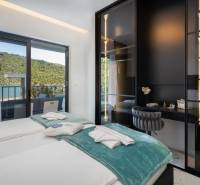 Hálószoba villában terasszal, kilátással a természetre és a tóra.