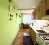 Konyha egy háromszobás lakásban, fa dekor padlóval és zöld falakkal.