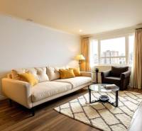 Világos nappali kanapéval egy háromszobás lakásban, fa dekoros padlóval, nagy ablakkal.