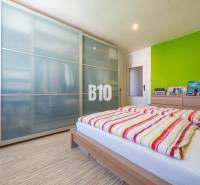 Hálószoba egy 4 szobás lakásban, fa dekor padlóval és tágas szekrénnyel.