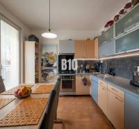 Konyha egy 4 szobás lakásban étkezőasztallal és beépített készülékekkel.