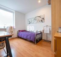 Hálószoba egy 4 szobás lakásban, fa dekorációjú padlóval és lila ágytakaróval.