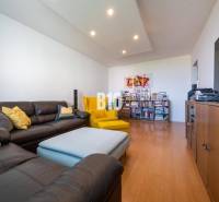 Nappali egy négyszobás lakásban, fa dekorációjú padlóval és kényelmes ülőhelyekkel.