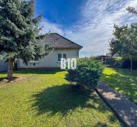 Családi ház Ondrejovcén füves kerttel, két fával és egy bokorral a járda mellett.