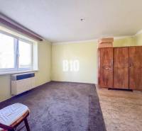 Szoba egy családi házban, szőnyeggel, régi szekrénnyel és fotellel.