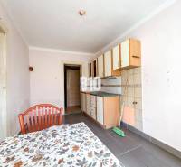 Konyha egyszerű szekrényekkel, csempékkel és asztallal egy családi házban.