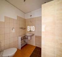 Fürdőszoba egy családi házban bézs csempével és fehér szaniter berendezésekkel.