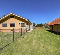 Családi ház Újszálláson két épülettel és füves telken, kerítéssel körülvéve.