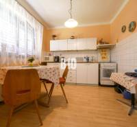 Családi ház konyhája étkezőasztallal, konyhabútorral és háztartási gépekkel.