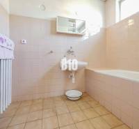 Fürdőszoba családi házban káddal és világos burkolatokkal a falakon.