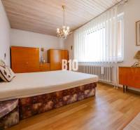 Hálószoba fa dekorációs padlóval egy családi házban, bútorokkal és csillárokkal.