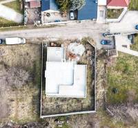 Építés alatt álló családi ház telken, kerttel és szomszédos házakkal körülvéve.