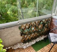 Üvegezett erkély fa dekorációval és növényekkel egy kétszobás lakásban.