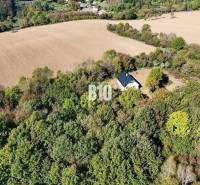 Ház Lackovban, erdővel és mezőkkel körülvéve, nyugodt vidéki táj.