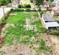 Telkek - lakóhely Bardoňován, erdősített parcellát mutatnak vidéki házakkal a háttérben.