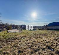 Telek betonalappal készen áll a lakhatásra, napos időjárás és környező táj.