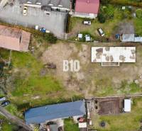 Légi felvétel egy telekről, épülettel és parkolóhelyekkel, ideális lakhatásra.