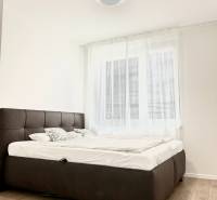 Hálószoba egy kétszobás lakásban, fa dekor padlóval és kényelmes ággyal.