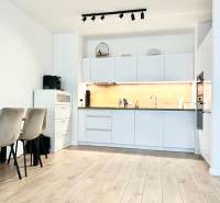 Konyha egy kétszobás lakásban, fa dekoros padlóval és étkezőasztallal.