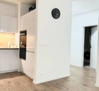 Konyha egy kétszobás lakásban, fa dekor padlóval és fehér bútorokkal.