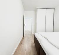 Szoba egy kétszobás lakásban, fa dekorációjú padlóval és beépített szekrénnyel.