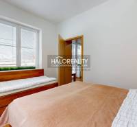 Hálószoba egy háromszobás lakásban, két ággyal és redőnyös ablakkal.