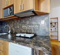 Nappali konyhával egy 3 szobás lakásban, fa mintázatú padlóval.