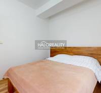 Hálószoba fa dekorációval, ággyal és kilátással a szomszédos nappalira egy háromszobás lakásban.