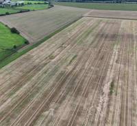 Szántóföld mezőgazdasági és erdőterületeken, Nová Ves nad Váhom, körülötte zöld rétekkel.