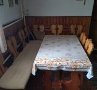 Ebédlő egy családi házban fa székekkel és asztallal, a falat képek és egy kereszt díszítik.