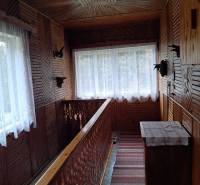 Családi ház belső tere fa díszítéssel, dekoratív korláttal és szőnyegekkel a folyosón.