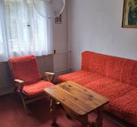 Egy szoba családi házban piros székekkel, asztallal és függönyökkel.