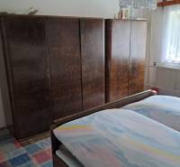 Hálószoba családi házban ággyal, szekrényekkel és színes mintás szőnyeggel.